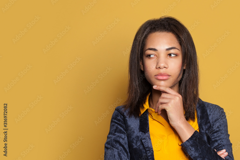 Young serious woman thinking on yellow background Young serious woman thinking on yellow background