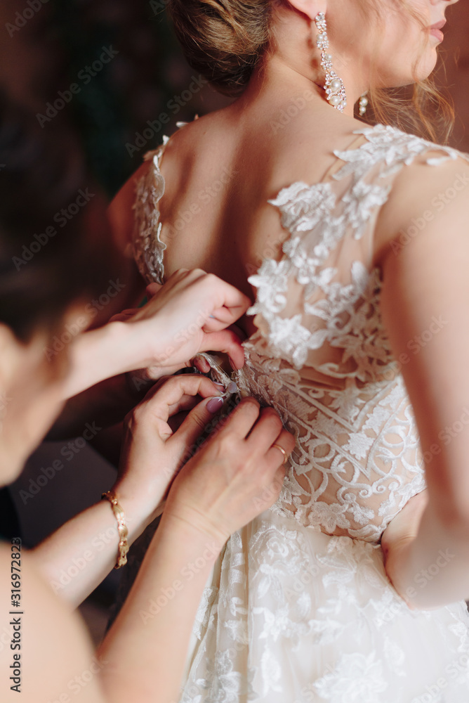 preparing the bride for the wedding in a wedding dress