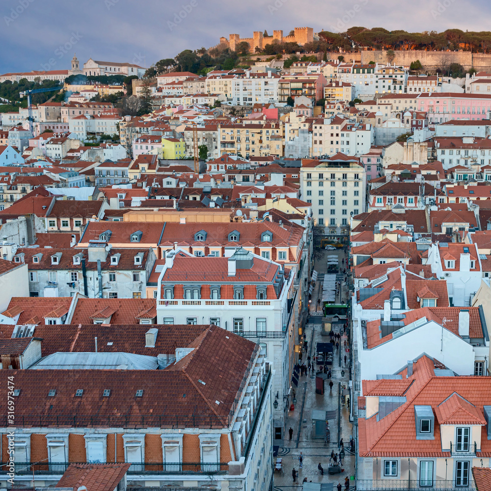 top view of the red tiled roofs of the Portuguese capital against the background of an old fortress and blue sky