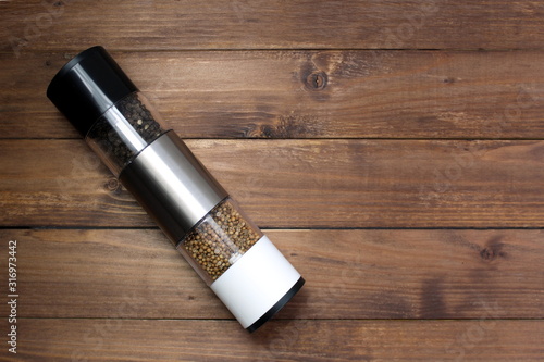 Double pepper mill lies on a wooden table