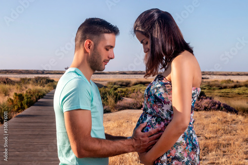 Pregnant happy couple with small dog photo