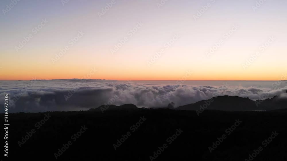 A beautiful sunset at Teida Mountain in Tenerife. An aerial view after the sun has settled down with the clouds under us. The sky is still golden while the land has become dark. A beautiful sunset at Teida Mountain in Tenerife. An aerial view after the sun has settled down with the clouds under us. The sky is still golden while the land has become dark.