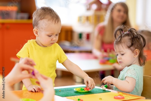 children toddlers playing clay in nursery or daycare or kindergarten