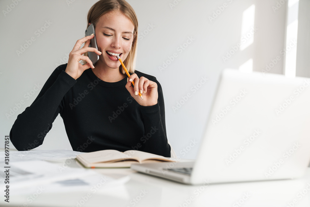 Smiling young blonde business woman talking by phone.