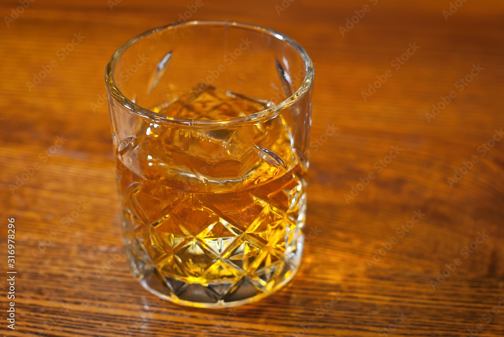 Yellow cocktail on bar counter. Whiskey, rum or brandy on a background of bar interior. Glass with booze on a wooden board.