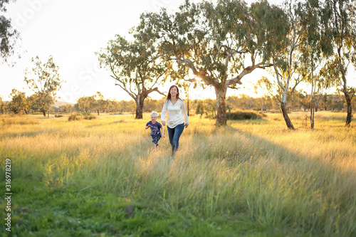 Mother and son playing together in a picturesque field with long grass at sunset. Family time. Mother-son bond. Beautiful image for mother's day with copy space. © Caseyjadew