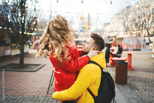 Young passionate couple having fun together and looking happy, handsome young man carrying his girlfriend while walking on the street. spending time together, having a date. urban background. Romantic