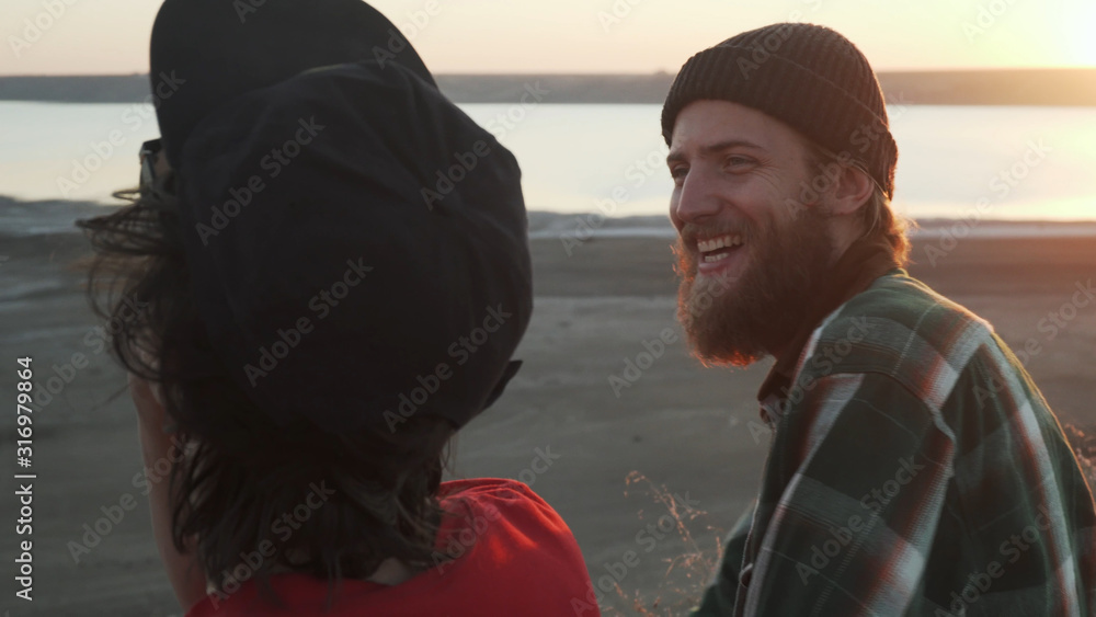 Two friends smoking joint with weed at seashore at sunset