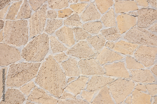 Old beige stone wall background texture close up. Old castle stone wall texture