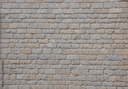 An example of ancient masonry as a cladding of external walls of castle. Natural stone background. Beige stone wall texture with torn edges