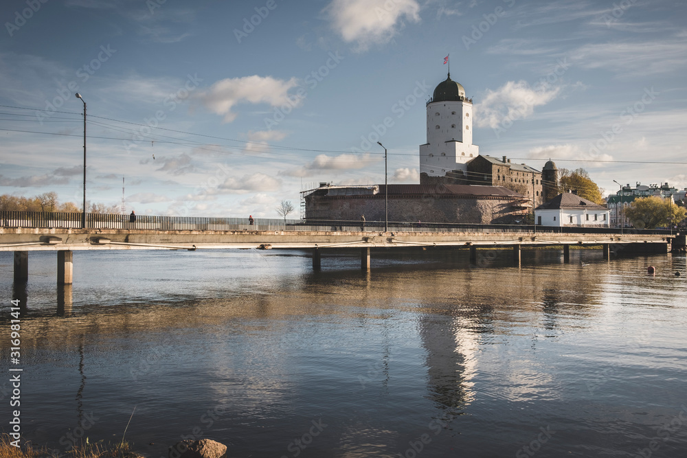 the tower of St. Olav of the Vyborg castle on the island is reflected in the water of the Gulf of Finland on a sunny autumn day