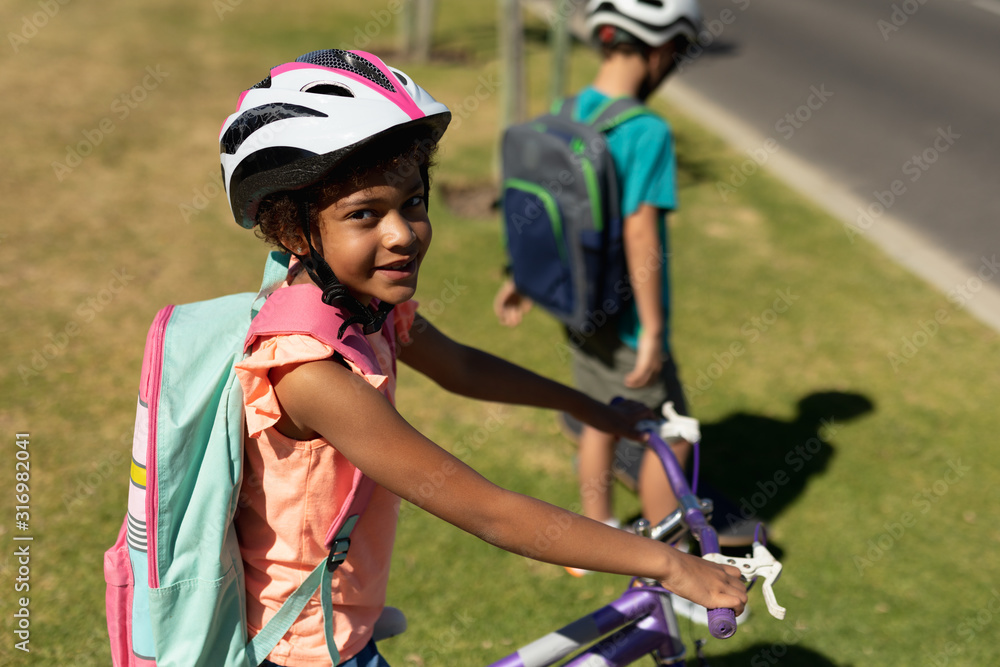 Schoolgirl sitting on a bicycle and wearing an helmet Schoolgirl sitting on a bicycle and wearing an helmet