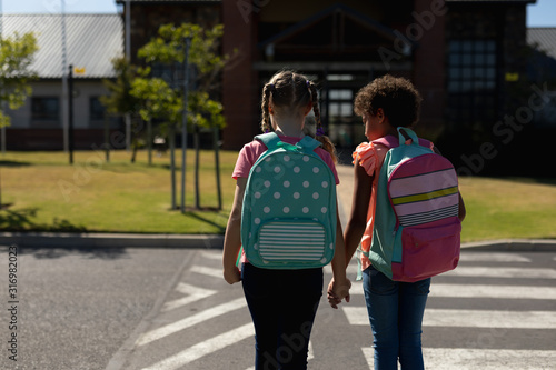 Two schoolgirls looking for traffic while waiting to cross the road