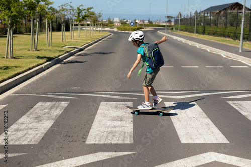 Schoolboy crossing the road on a skateboard