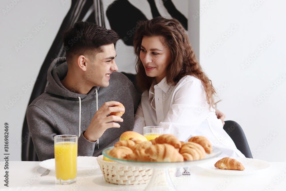A couple of young people have breakfast with orange juice and croissants A couple of young people have breakfast with orange juice and croissants