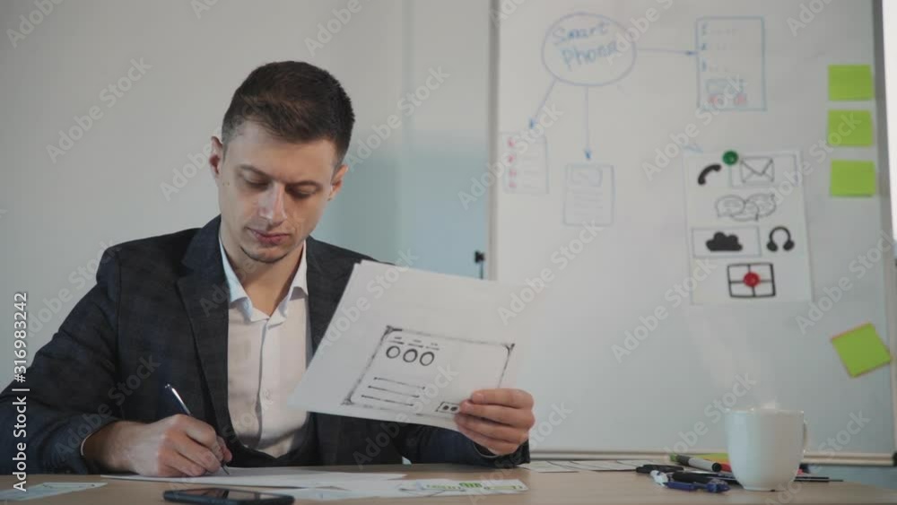 American man architect working with new blueprint and writing at desk in agency room. Concept create ux design for people. Portrait of elegant businessman doing creative paperwork, holding and American man architect working with new blueprint and writing at desk in agency room. Concept create ux design for people. Portrait of elegant businessman doing creative paperwork, holding and