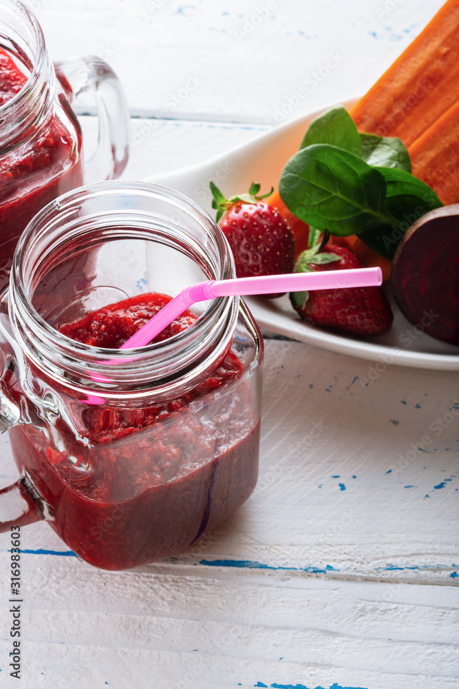 Detox smoothie from apple, beet, carrots, strawberry and spinach in mason jar on old, wooden background. Ingredients for a detox smoothie. High key. Selective focus. Detox smoothie from apple, beet, carrots, strawberry and spinach in mason jar on old, wooden background. Ingredients for a detox smoothie. High key. Selective focus.