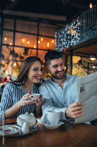 romantic couple in restaurant drinking tea and reading press