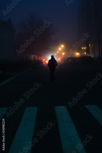 Blurred figure of a man in the fog of a night city