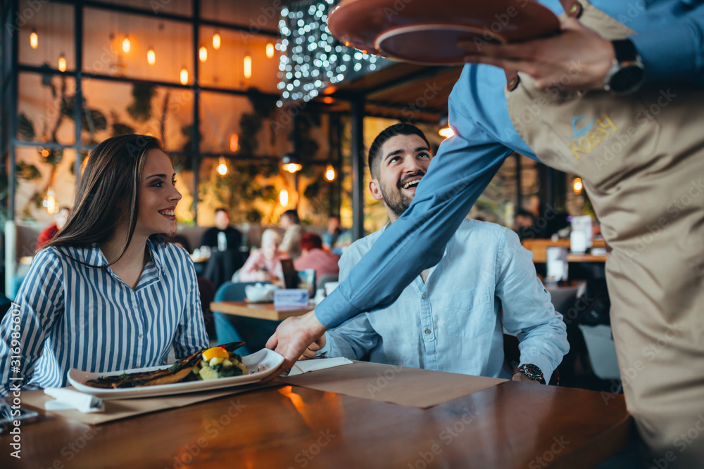 couple in restaurant . waiter serving customer with food