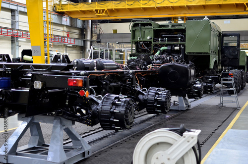 Heavy duty truck for transport missile defence system and non-standard cargo. Industrial workshop for the production of military trucks, wheel chassis and vehicles. Wheeled tractor background