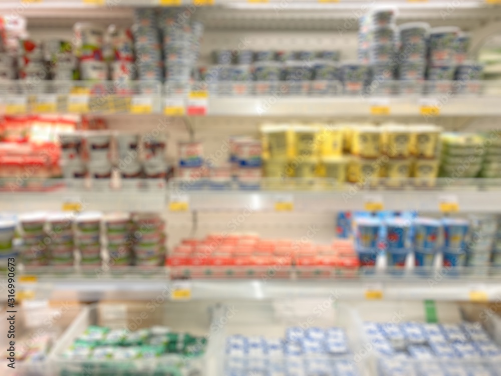 Supermarket defocused blurred background. Fridge with yogurt, cheese and butter