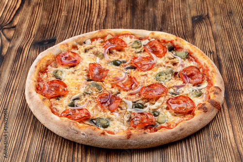 Very hot and spicy pizza with jalapeno, pepperoni and red onion on wooden background
