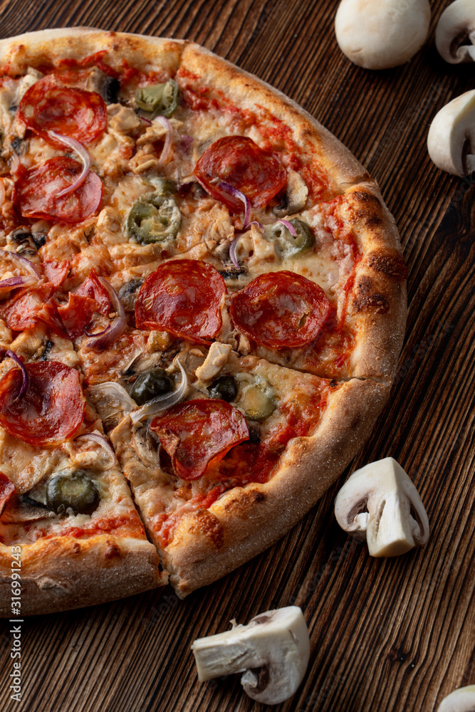 Close up of hot and spicy pizza with jalapeno, pepperoni and red onion on dark wooden background