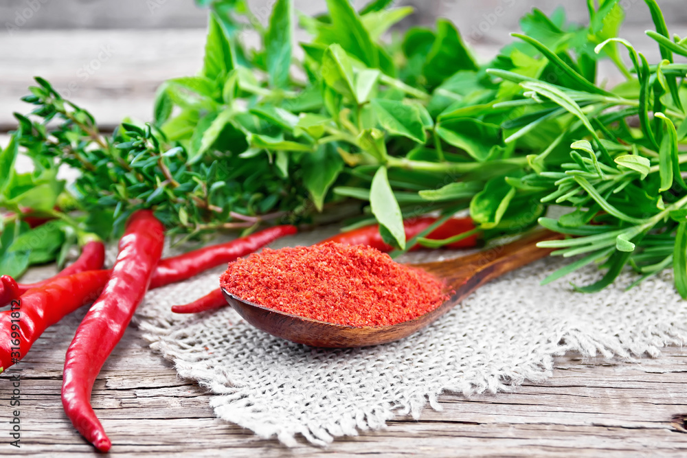 Peppers red powder in wooden spoon on old board Peppers red powder in wooden spoon on old board