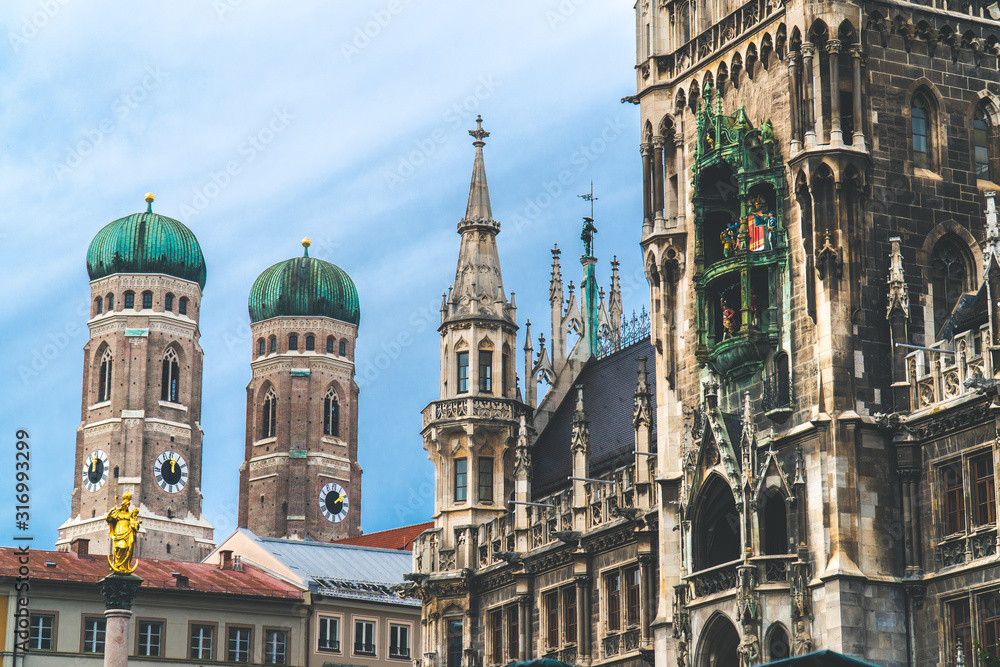 Obraz premium Nowy Ratusz, Neues Rathaus na głównym placu Marienplatz, budynek władz miejskich z zegarem wieżowym. Styl gotycki. Sfotografowany od dołu. Szerokie ujęcie z Monachium Frauenkirche w tle. Szeroki