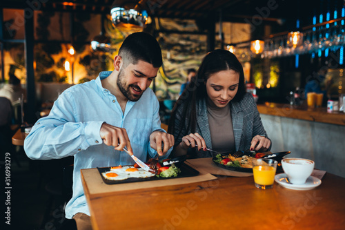 happy young couple having lunch in restaurant