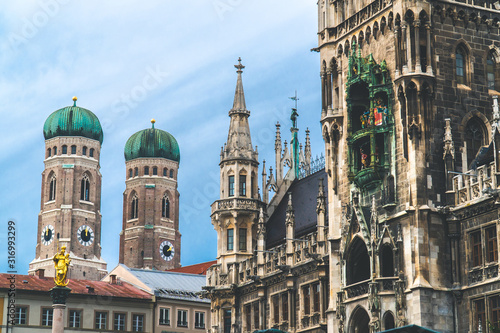 The New Town Hall, Neues Rathaus on Marienplatz main square, city government building with a tower clock. Gothic style. Photographed from below. Wide shot with Munich Frauenkirche in background. Wide  © Kuma Media