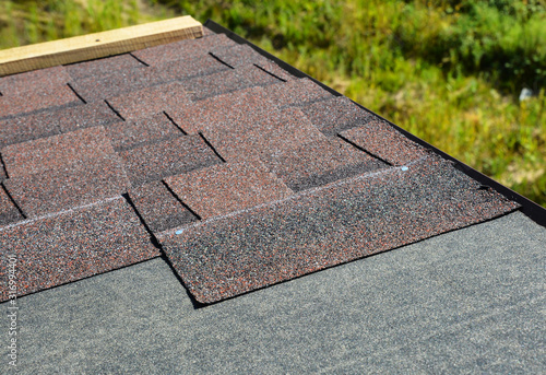 Laying asphalt shingles on house rooftop. Roofing construction concept