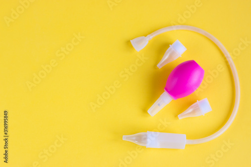 The concept of medicine and hygiene of the child. Children's nasal aspirator on a yellow background. Copyspace.
