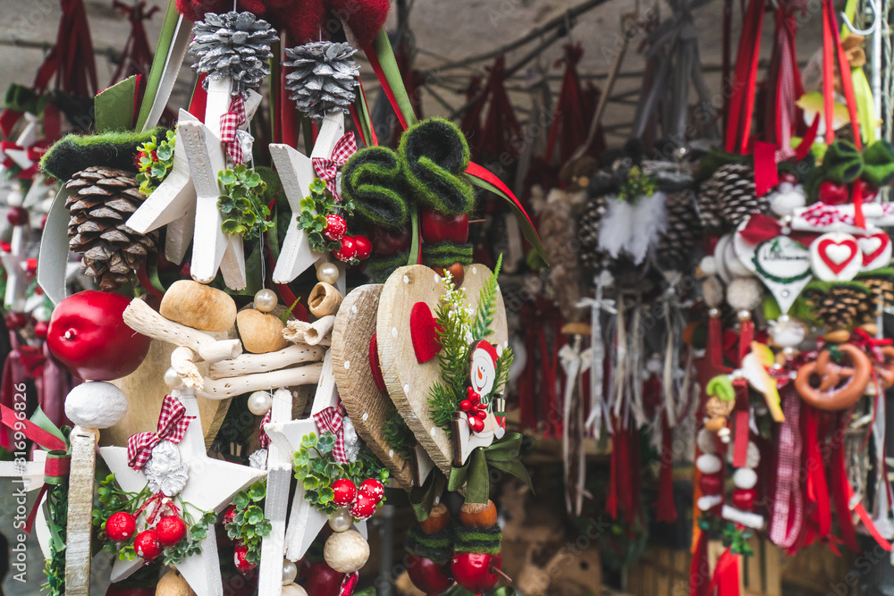 Naklejka premium Traditional Christmas decorations for sale at a Christmas market stand on a sunny winter day in December. Red and green hanging toys and decorations. Close up shot