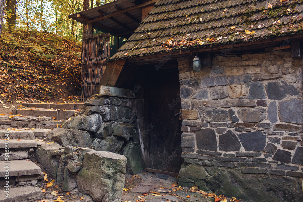 old stone granite house with staircase on slope in autumn forest. old stone granite house with staircase on slope in autumn forest.