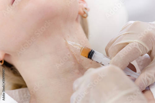 Young woman beautician makes plasmolifting procedure with syringe on neck young pretty female client lying on chair in medical beauty center. Plasma therapy plasma recovery. Modern cosmetology