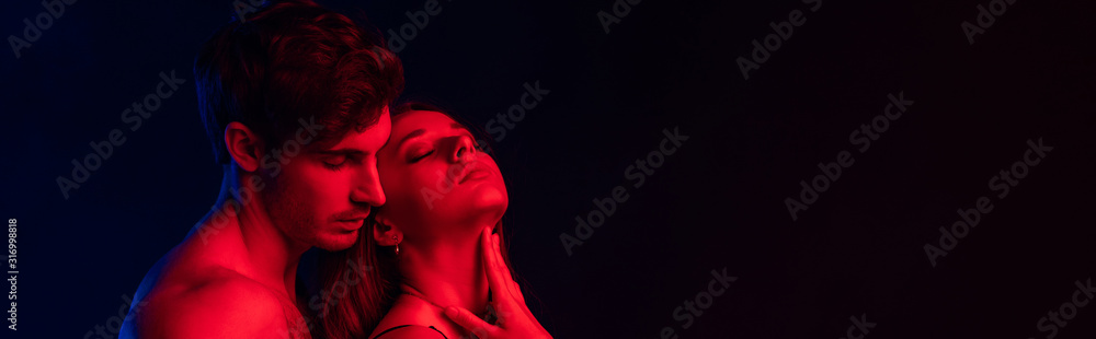 passionate undressed sexy young couple in red light isolated on black, panoramic shot