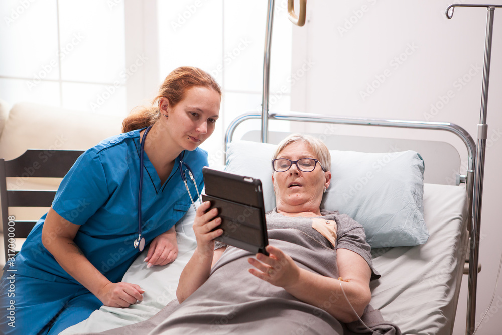 Obraz premium Portrait of old woman in nursing home using tablet computer