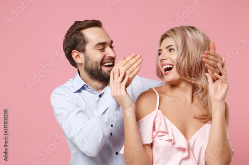 Laughing young couple two guy girl in party outfit celebrating posing isolated on pastel pink background. People lifestyle Valentine's Day Women's Day birthday holiday concept. Looking at each other.