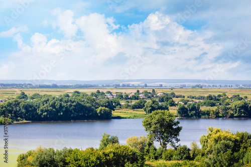 Summer landscape with river, green shores and beautiful sky with white clouds_