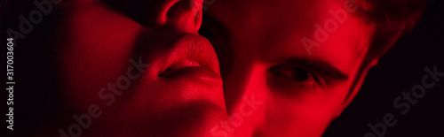 close up view of passionate young couple kissing in red light, panoramic shot
