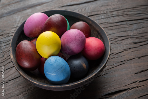 Colorful Easter eggs in bowl on wooden table. Attribute of Easter celebration.