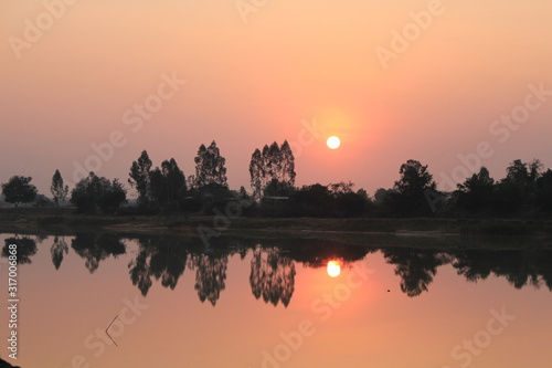  silhouette tree in asia with sunset.Tree silhouetted against a setting sun.Dark tree on open field dramatic sunrise and reflection in water.