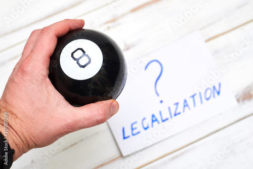 Legalization word with a question mark and a ball of predictions on a light wooden background. The concept of legal decisions taken at random. photo