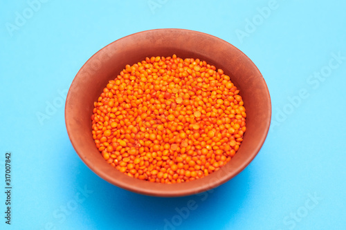 lentil grains in a plate on a blue background.