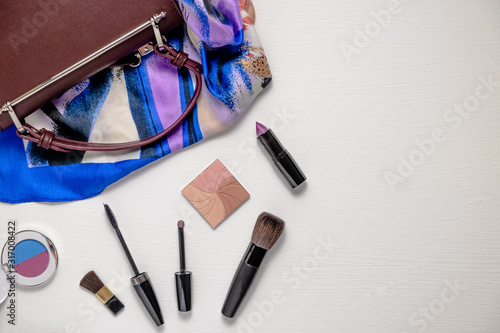 Women's accessories on a white background, bag. scarf, lipstick, blush, brushes, mascara. Top view.