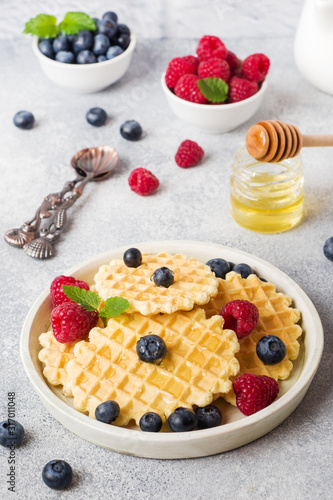 Corrugated waffle cookies with fresh raspberries and blueberries on a concrete background. Copy space.