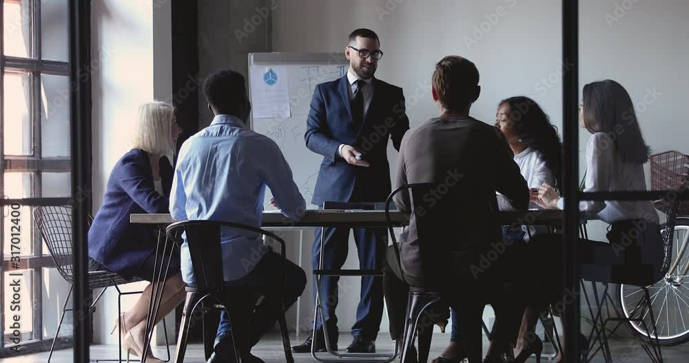 Smiling businessman leader give business presentation teach diverse executive group Smiling businessman leader give business presentation teach diverse executive group