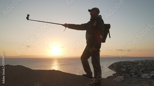 Senior traveler start vlogging standing on a hill at sunrise